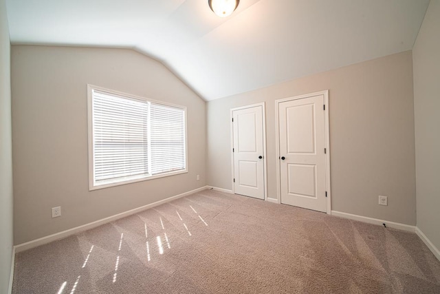 unfurnished bedroom with lofted ceiling, carpet, and baseboards