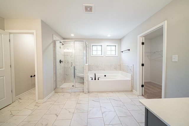 bathroom with marble finish floor, a spacious closet, a stall shower, and a garden tub