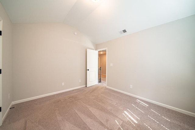 empty room featuring vaulted ceiling, baseboards, visible vents, and light colored carpet