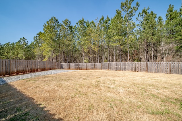 view of yard featuring a forest view and a fenced backyard