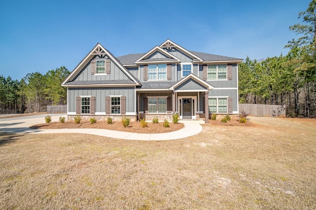 craftsman inspired home featuring roof with shingles, fence, board and batten siding, and a front yard