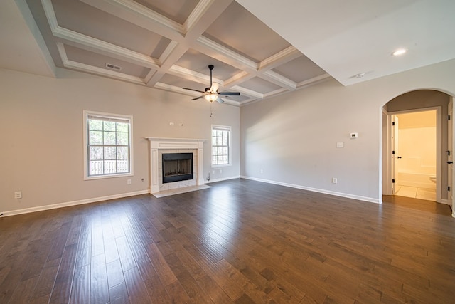 unfurnished living room featuring coffered ceiling, dark wood-style flooring, a wealth of natural light, and a high end fireplace