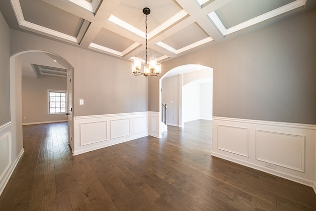 spare room featuring arched walkways, coffered ceiling, dark wood-type flooring, beam ceiling, and a notable chandelier