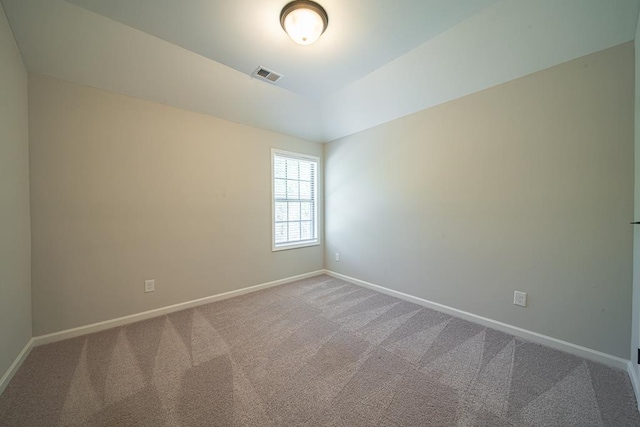 empty room featuring baseboards, visible vents, vaulted ceiling, and carpet flooring