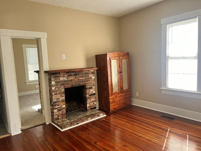 unfurnished living room with plenty of natural light, dark hardwood / wood-style flooring, and a brick fireplace