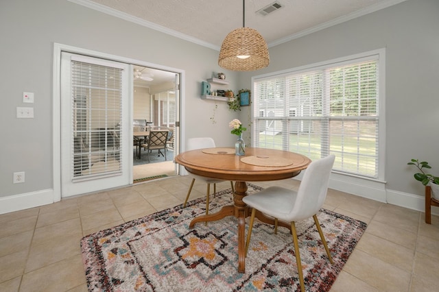 tiled dining space with crown molding, a wealth of natural light, baseboards, and visible vents