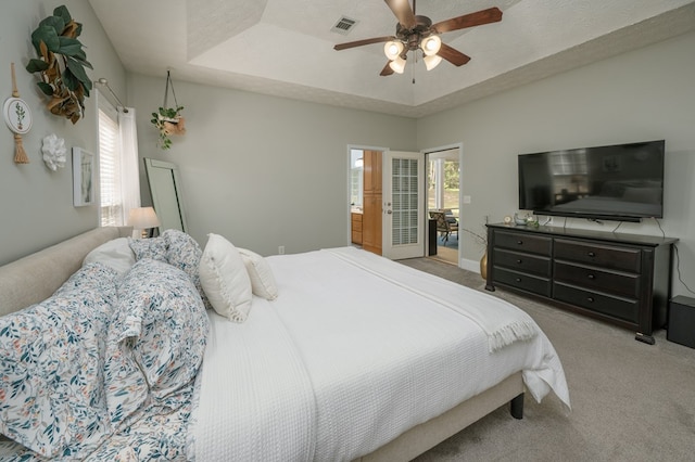 bedroom featuring carpet, visible vents, a raised ceiling, and ceiling fan