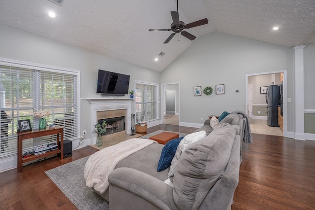 living area featuring wood finished floors, a fireplace, a ceiling fan, and a healthy amount of sunlight