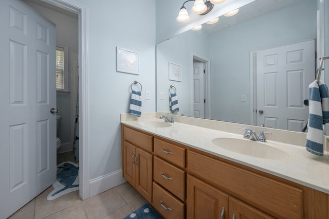bathroom featuring toilet, tile patterned floors, double vanity, and a sink