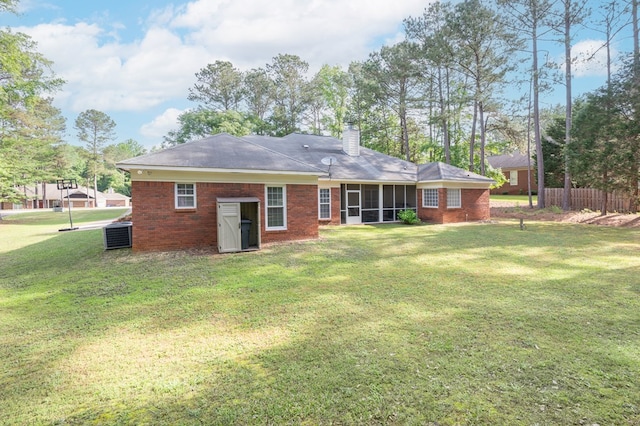 rear view of property with a yard, a sunroom, a chimney, and brick siding