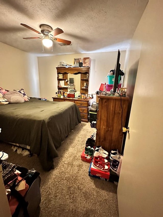 bedroom with ceiling fan, carpet floors, and a textured ceiling