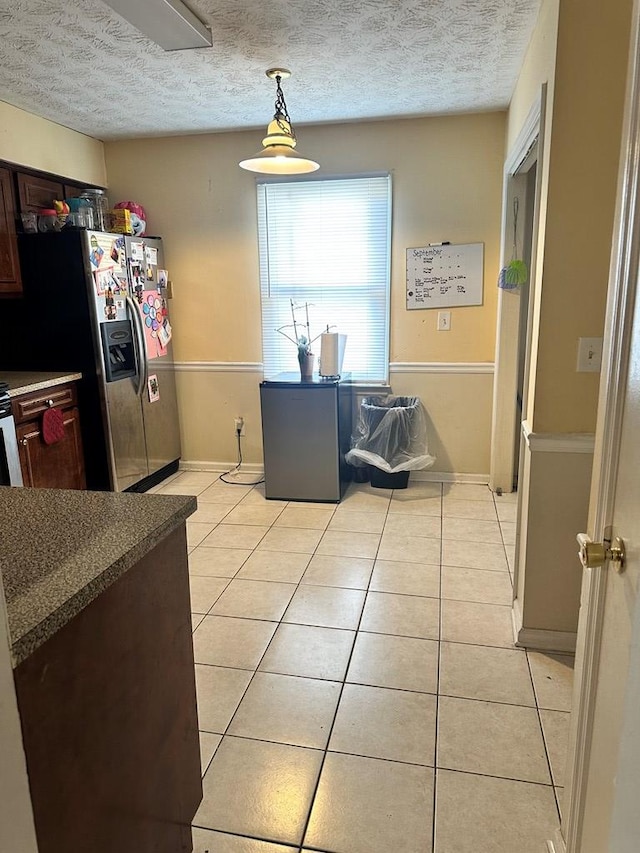 kitchen featuring stainless steel refrigerator with ice dispenser, a textured ceiling, and light tile patterned flooring