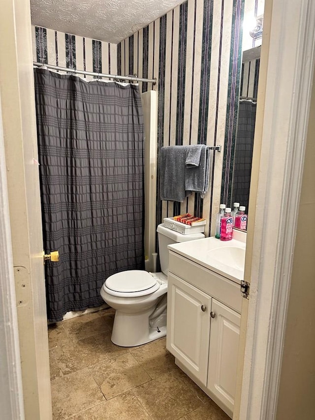 full bathroom featuring shower / bath combo with shower curtain, vanity, a textured ceiling, and toilet