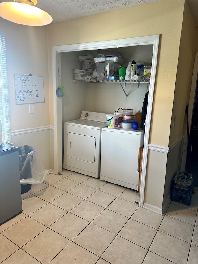 laundry room featuring washer and dryer, a textured ceiling, and light tile patterned flooring