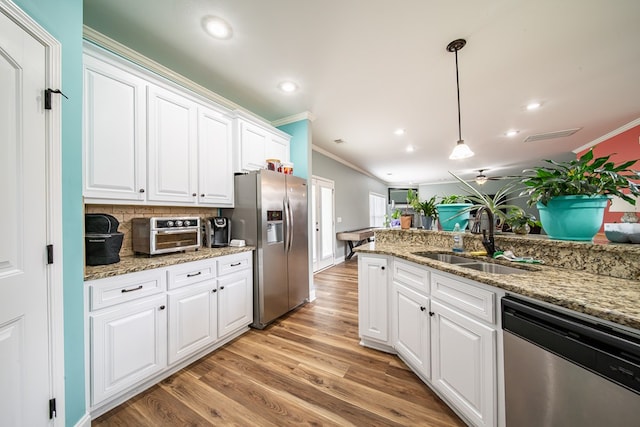 9597 Yarbrough Rd, Midland, GA 31820 - kitchen featuring appliances with stainless steel finishes, ornamental molding, a sink, white cabinets, and light wood-type flooring