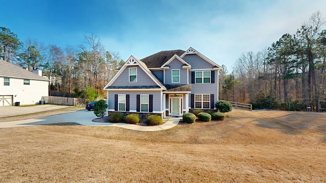 craftsman house with fence and a front lawn