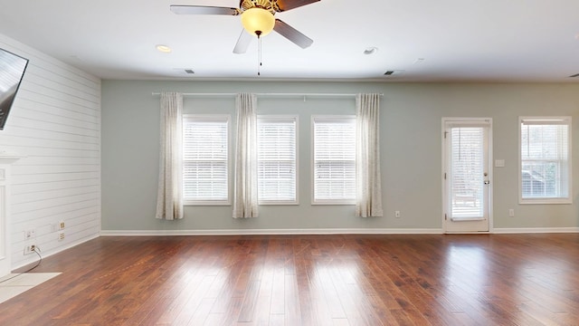 unfurnished room with baseboards, wood finished floors, a wealth of natural light, and a ceiling fan