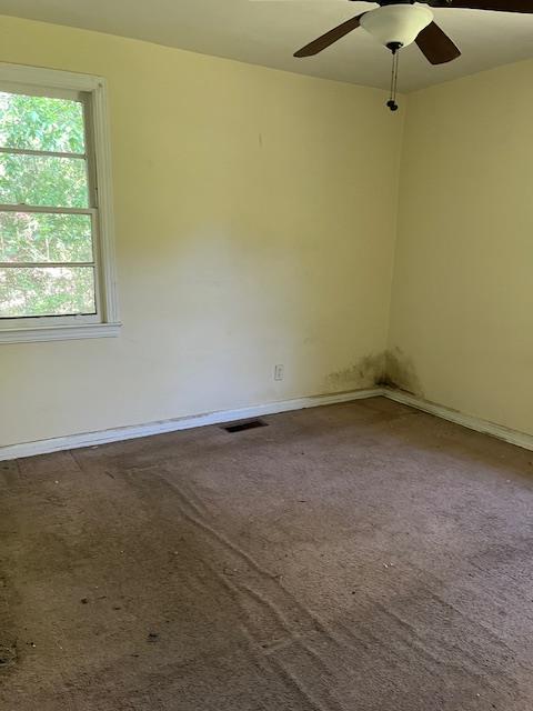 carpeted empty room featuring baseboards, a ceiling fan, and visible vents