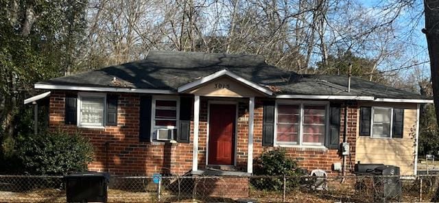 ranch-style home with brick siding, cooling unit, and a fenced front yard