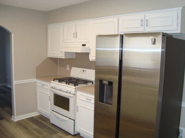 4118 Terrace Pointe Dr, Columbus, GA 31909 - kitchen with stainless steel fridge with ice dispenser, white range with gas stovetop, under cabinet range hood, dark wood finished floors, and white cabinetry