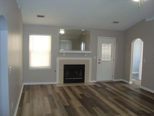 4118 Terrace Pointe Dr, Columbus, GA 31909 - unfurnished living room featuring arched walkways, a tile fireplace, and wood finished floors