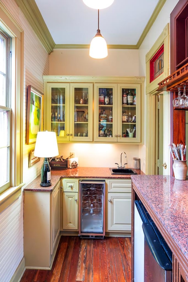 bar featuring sink, hanging light fixtures, stainless steel dishwasher, dark hardwood / wood-style floors, and beverage cooler