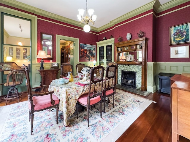 dining space with a chandelier, crown molding, a fireplace, and dark wood-type flooring