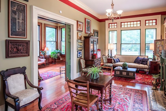 living area with crown molding, hardwood / wood-style floors, and an inviting chandelier