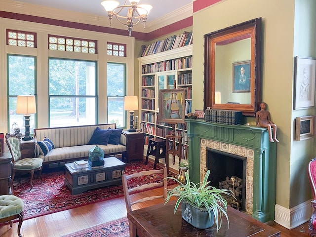 sitting room featuring hardwood / wood-style floors, an inviting chandelier, ornamental molding, and a premium fireplace