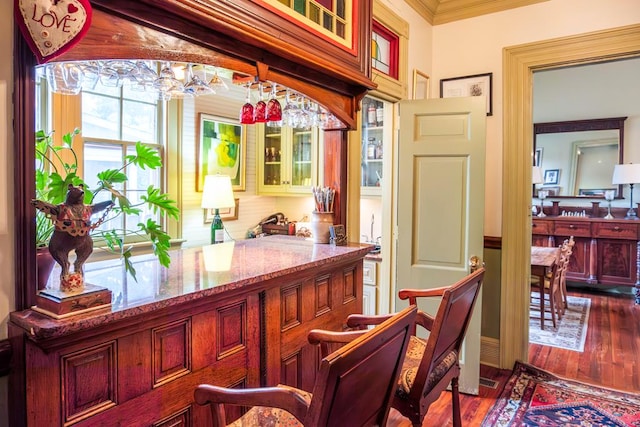 bar featuring hanging light fixtures, light stone counters, dark hardwood / wood-style flooring, a notable chandelier, and crown molding