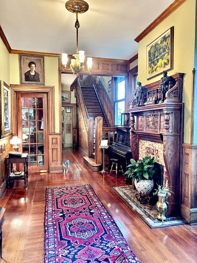 living area with wood-type flooring, an inviting chandelier, and ornamental molding