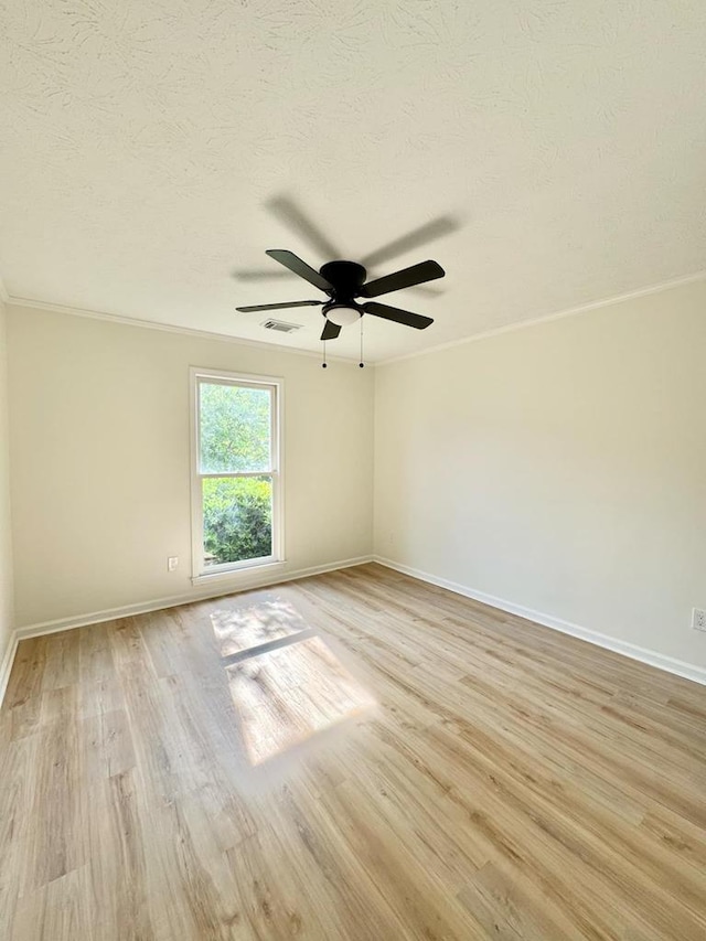 empty room featuring ceiling fan, visible vents, crown molding, baseboards, and light wood-style floors