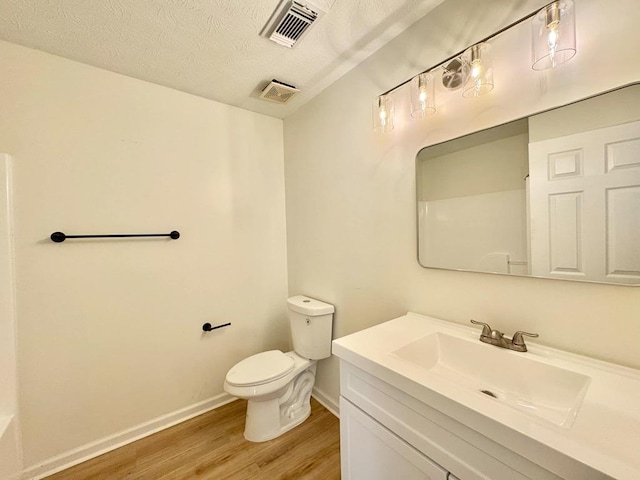 bathroom with toilet, baseboards, visible vents, and wood finished floors