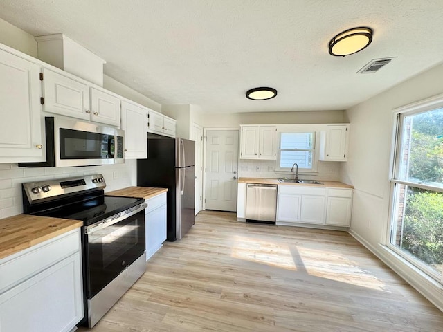 kitchen featuring visible vents, white cabinets, tasteful backsplash, a sink, and appliances with stainless steel finishes