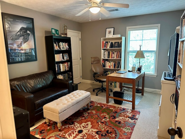 carpeted office space featuring baseboards, a ceiling fan, a textured ceiling, and visible vents