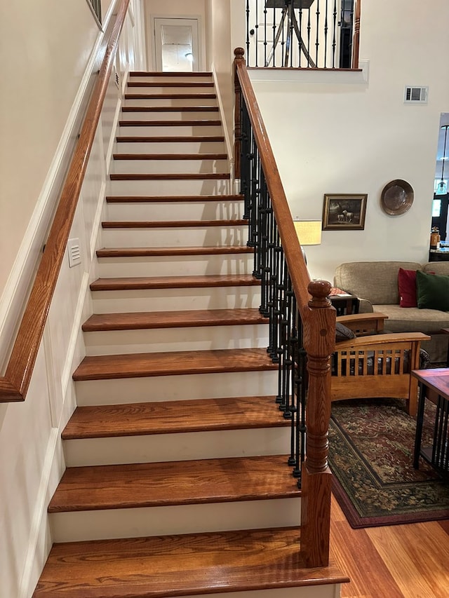 stairway featuring wood finished floors and visible vents