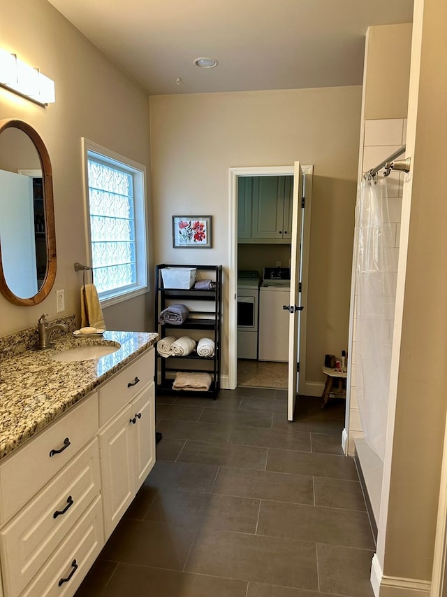 full bath featuring curtained shower, washer and clothes dryer, tile patterned flooring, and vanity