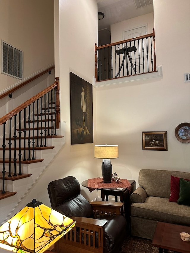 living area with stairway, a towering ceiling, and visible vents