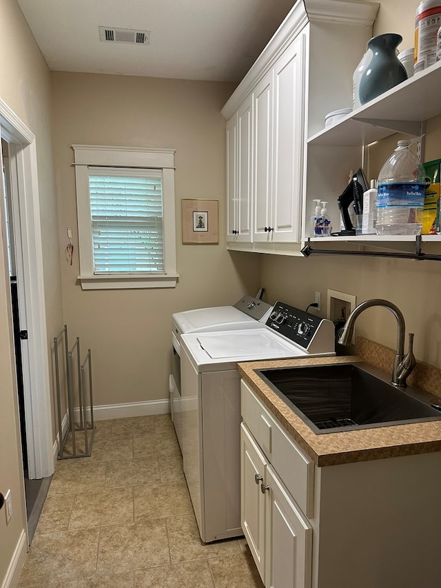 laundry area featuring visible vents, washing machine and dryer, baseboards, a sink, and cabinet space