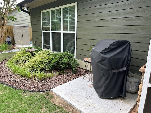 view of patio / terrace with an outdoor structure, grilling area, and a shed