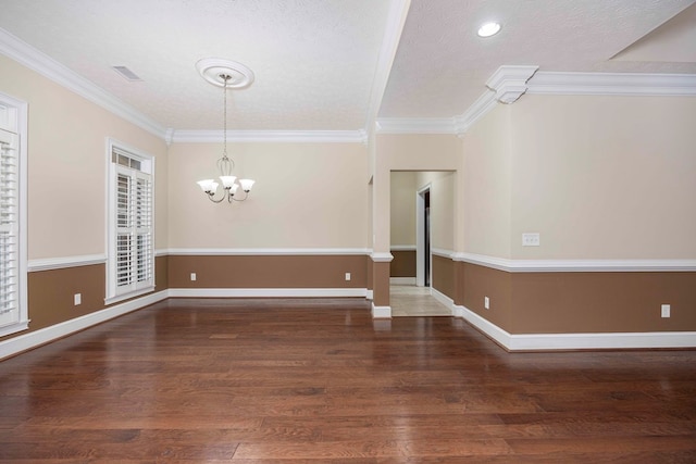 spare room featuring baseboards, ornamental molding, wood finished floors, and an inviting chandelier