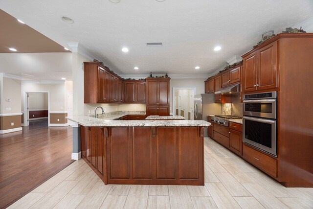 kitchen featuring light stone counters, wood finish floors, stainless steel appliances, a peninsula, and under cabinet range hood