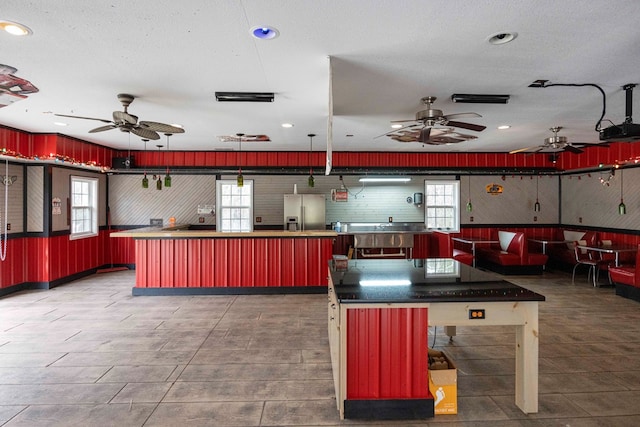 kitchen with recessed lighting, a center island, a textured ceiling, and stainless steel fridge with ice dispenser