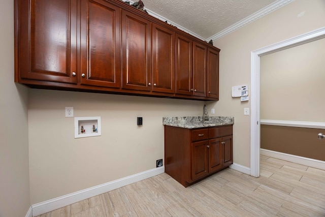 clothes washing area featuring cabinet space, light wood finished floors, baseboards, a textured ceiling, and washer hookup