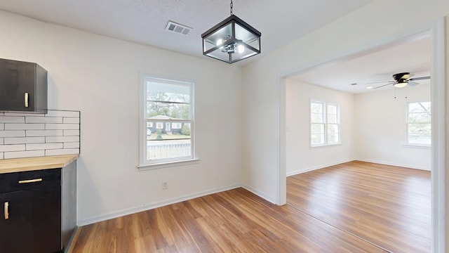 unfurnished dining area featuring light wood finished floors, baseboards, visible vents, and a wealth of natural light