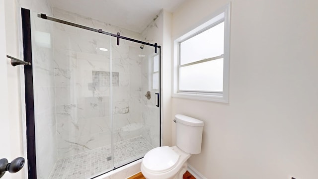 bathroom featuring a marble finish shower, toilet, and baseboards