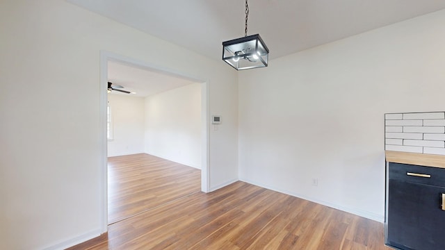 unfurnished dining area featuring baseboards and light wood finished floors