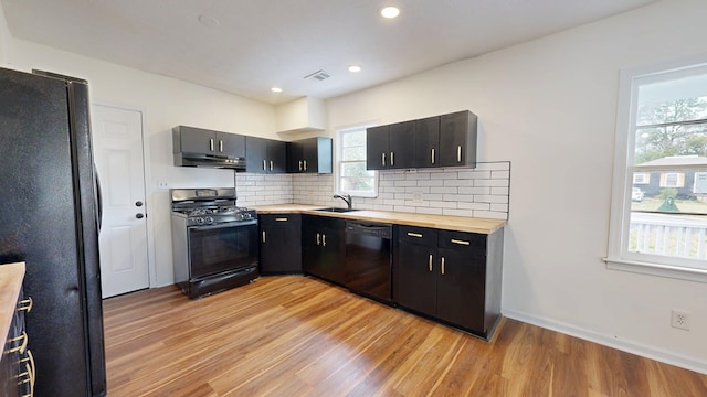 kitchen with dark cabinetry, visible vents, a sink, black appliances, and under cabinet range hood