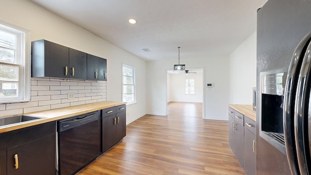 kitchen with fridge with ice dispenser, black dishwasher, light wood finished floors, decorative backsplash, and wooden counters