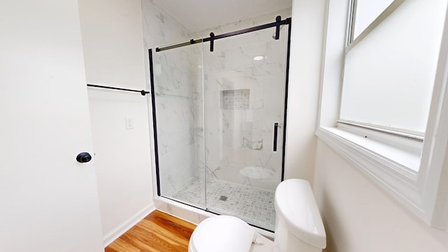 bathroom featuring toilet, wood finished floors, and a marble finish shower